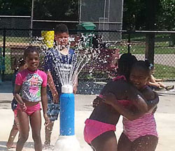 Girls embrace eachother at sprinkler